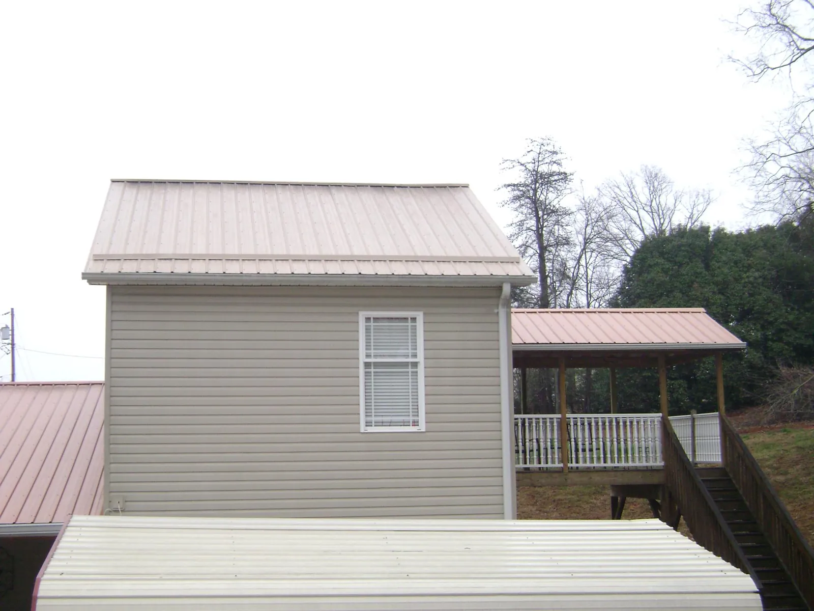 Tan metal roofs on a two story addition and attached porch, from a Roof Replacement job in Melbourne